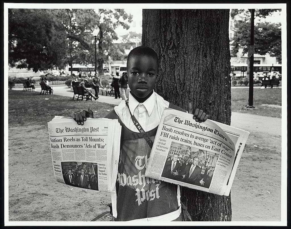 A newsboy holding a special edition newspaper in Farragut Square, Washington DC